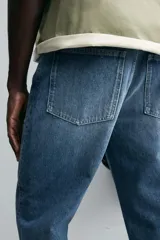 Pantalón de jean azul de tiro medio, corte flare, con cinco bolsillos y cierre frontal con cremallera y botón.