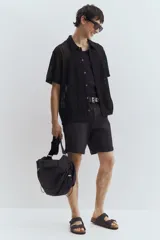 Short de denim negro de cinco bolsillos con corte ajustado en cintura, muslos y bajo, y piernas rectas.