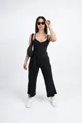 Mono negro de breteles finos con escote recto, corte a la cintura con lazo y pantalón capri de pierna ancha.