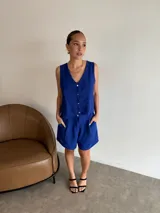 Conjunto de dos piezas color rojo vibrante, compuesto por un chaleco sin mangas con escote en V y botones frontales, y un short de tiro alto con pliegues y bolsillos laterales.