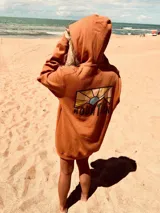 Buzo hoodie color ladrillo con estampado en la espalda de montañas y sol.