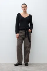 Sweater de tejido de punto negro, con escote en V pronunciado y mangas largas acampanadas. Presenta un lazo ancho anudado a la cintura.