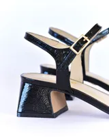 Sandalias de charol negro con taco cuadrado de 5 cm, plantilla, capellada y forro de cuero.