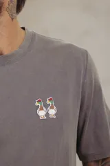 Remera gris con cuello redondo y mangas cortas. Estampado pequeño de dos patos en el pecho.