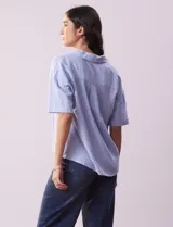 Blusa celeste de lino marca Cupio, con cuello con solapa, escote en V y delantera cruzada.