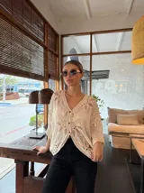Blusa color crema de tejido calado con mangas 3/4 y cuello en V.