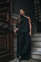 Pantalón negro de corte amplio con pinzas en la cintura, regulable con elástico y tiras.