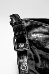 Bandolera negra de cuero sintético con correa de hombro ajustable y cierre superior con cremallera.
