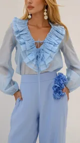 Blusa celeste con cuello en V y volados, mangas largas abullonadas y lazos en el escote.