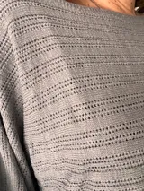 Sweater de tejido calado color gris, con cuello redondo y mangas globo.