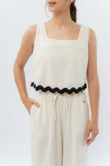 Top de lino color crudo, con escote cuadrado y detalle de guarda ondulada negra en el ruedo.