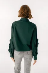 Camisa celeste con cuello clásico, cierre frontal con botones y mangas largas con volados.