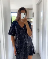 Vestido corto negro con lentejuelas, escote en V y mangas cortas.