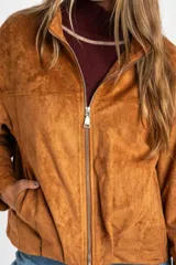 Campera tipo bomber de cuero vegano color camel, con cierre frontal y cuello alto. Presenta un calce oversize y puños ajustados con botón.