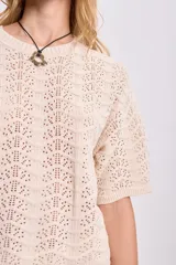 Top de punto calado color crudo con cuello redondo y mangas cortas.