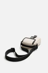 Bandolera vertical negra de acabado engomado con compartimento principal con cierre de cremallera y bolsillo interior plano. Bolsillo frontal con cierre de hebilla de liberación rápida. Asa de hombro ajustable y extraíble.