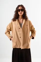 Chaqueta tipo sobrecamisa o abrigo ligero color camel, con cuello solapa de color marrón oscuro, cierre frontal de botones y bolsillos laterales.