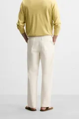 Pantalón chino color crema de corte recto, confeccionado en tejido de algodón con elasticidad. Cuenta con bolsillos frontales y traseros de plastrón con botón. Cierre frontal con cremallera y botón.