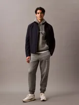 Pantalón de jogging gris con cintura elástica, bolsillos laterales y logo de Calvin Klein Jeans en la pierna. Confeccionado en mezcla de algodón y poliéster.