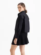 Camisa blanca de poplin de algodón con fit cómodo y largo que cubre hasta debajo de la cintura. Presenta botones ocultos en cartera y puños, y punteras de níquel en el cuello.