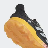Championes deportivos Adidas Adipower Field Hockey 2.1, color negro con tres franjas plateadas en el lateral. Posee una entresuela gruesa de color amarillo mostaza y suela de goma color caramelo con tacos multidireccionales.