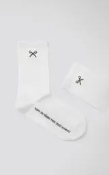 Medias blancas de algodón, caña media/larga (3/4), con bordado de tijeras en la parte superior y texto en la planta del pie que dice "ropa sin género para seres humanos".