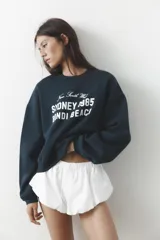 Sudadera azul marino de cuello redondo y manga larga con estampado frontal que dice "New South Wales Sydney 1985 Bondi Beach" en color blanco.