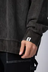 Buzo de cuello redondo y corte oversize en tela friza, color gris con efecto acid wash. Presenta un estampado frontal en color verde lima con un diseño abstracto.