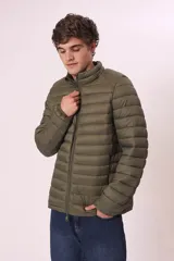 Campera puffer color verde militar, con cuello alto y cierre frontal. Diseño acolchado horizontal.