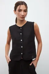 Chaleco negro sin mangas con cuello redondo y cierre frontal con botones blancos.