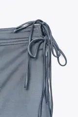 Falda pantalón negra de tiro alto con aberturas laterales y cierre cruzado con lazadas y cremallera oculta.