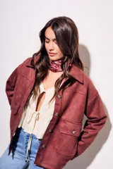 Sobrecamisa color borgoña de gamuza sintética con cuello camisero, cierre frontal con botones a tono, bolsillos de parche con solapa en el pecho y mangas largas con puños abotonados.