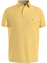 Chomba amarilla de Tommy Hilfiger, modelo 1985, de corte regular, con cuello tipo chomba, cartera de dos botones, logo bordado en el pecho y diseño de rayas en el interior del cuello.