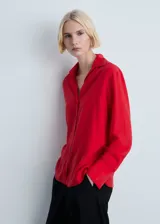 Camisa roja de tejido fluido con cuello camisero, cierre frontal con botones, mangas largas con puños abotonados y aberturas laterales.