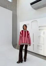Sweater de punto oversize a rayas verticales rosas y bordó, con cuello alto y puños con ribete celeste.