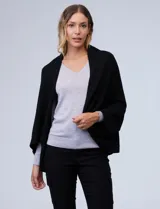 Cardigan negro de tejido suave, estilo poncho o capa, con cuello tipo chal y mangas amplias.