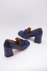 Zapato clásico de cuero azul marino, con aplique decorativo en el empeine y taco cuadrado.
