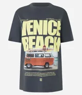 Remera gris con estampa de la frase "Venice Beach" en amarillo y una imagen de una camioneta con tablas de surf.