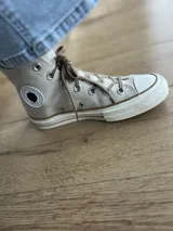 Zapatillas de lona blancas de caña alta con cordones y puntera de goma. Logo de durazno engomado en la base y en la cara interna.