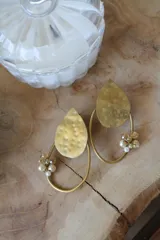 Par de aros colgantes dorados con forma de gota y aro ovalado. Decorados con cuentas de cristal facetado color ámbar y perlas pequeñas.