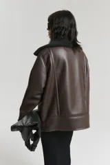 Campera marrón estilo aviador con cuello de piel sintética negra, cierre frontal con cremallera y bolsillos laterales.