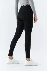 Pantalón de jean negro, corte skinny, tiro medio, con logo bordado y pasacinto.