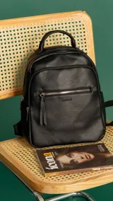 Mochila color caramelo de símil cuero, con dos bolsillos frontales con cierre y bolsillos laterales abiertos. Interior forrado con dos bolsillos con cierre y uno abierto. Tiene asa de mano y correas regulables.