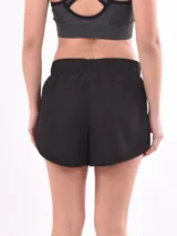 Short de running negro, ligero y holgado, con cintura elástica fruncida y bolsillos laterales. Presenta un forro interior y detalles de malla en los laterales.
