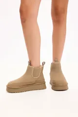 Bota tipo chelsea color camel, confeccionada en gamuza con interior forrado en piel sintética. Presenta elásticos laterales, tirador en la parte trasera y plataforma alta con suela dentada.