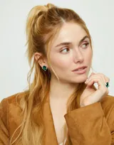 Par de aros tipo botón de aleación de metales bañados en plata de ley, con cristal facetado verde de forma ovalada.