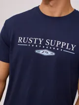 Remera color crema de manga corta con estampado frontal con el texto "Rusty Supply Surfboards" en color rojo y negro.