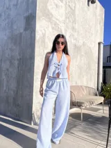 Conjunto celeste a rayas verticales blancas, compuesto por un top halter con lazos y un pantalón palazzo con cintura elastizada.