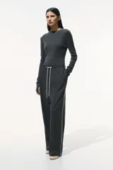 Pantalón negro de sarga suave con cintura elástica, cordón de ajuste en color contrastante y franjas laterales finas. Modelo de corte holgado con tiro alto, bolsillos laterales discretos y bolsillos insertados decorativos atrás. Piernas amplias con pliegues adelante y atrás.