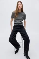 Jean de cinco bolsillos en denim de algodón, color negro lavado. Presenta un corte de tiro alto con piernas curvas de estilo baggy, con volumen en cintura y cadera, y ligeramente más ajustado desde el muslo hacia abajo.